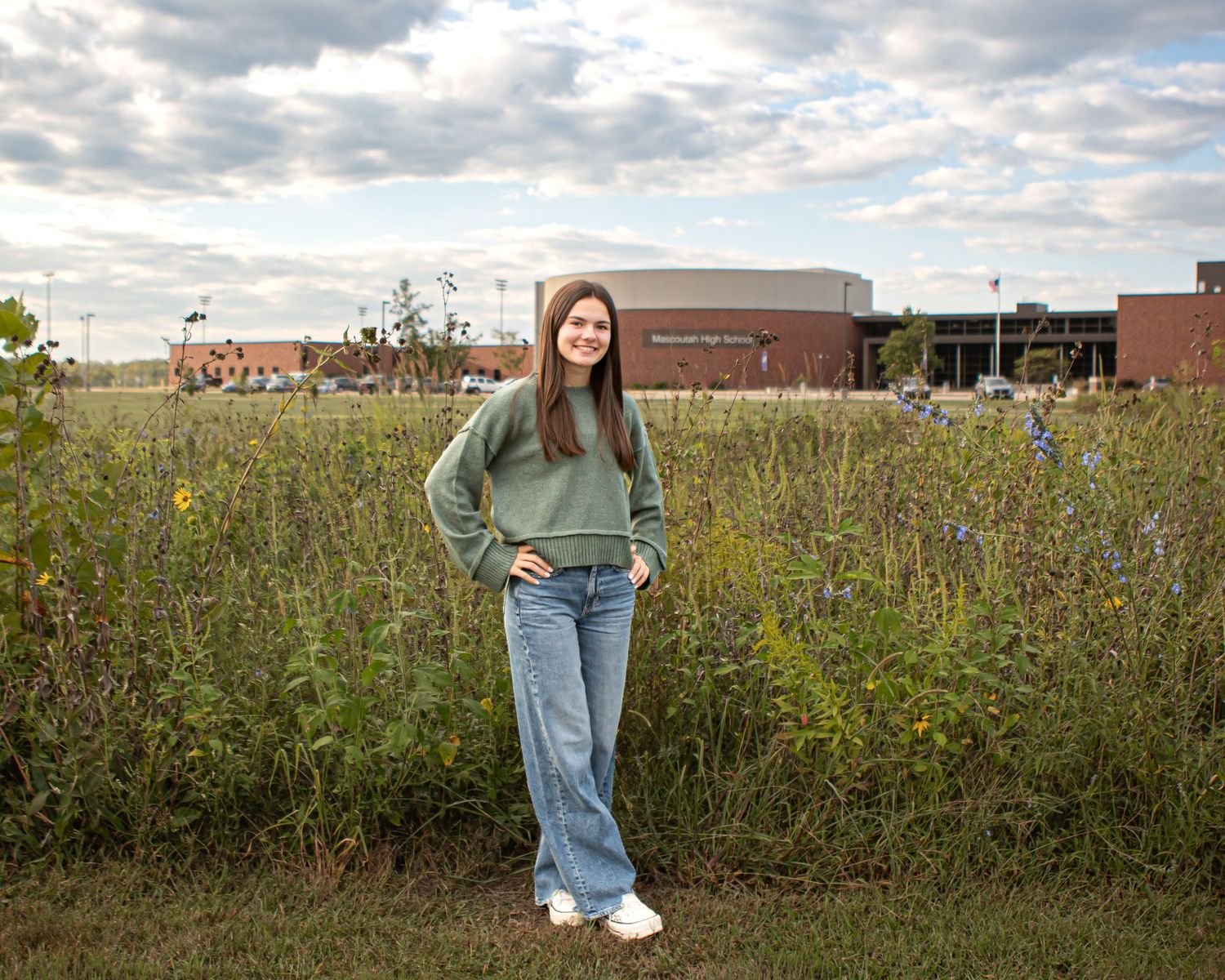 Candid outdoor fashion shot in a wildflower field with cloudy sky.