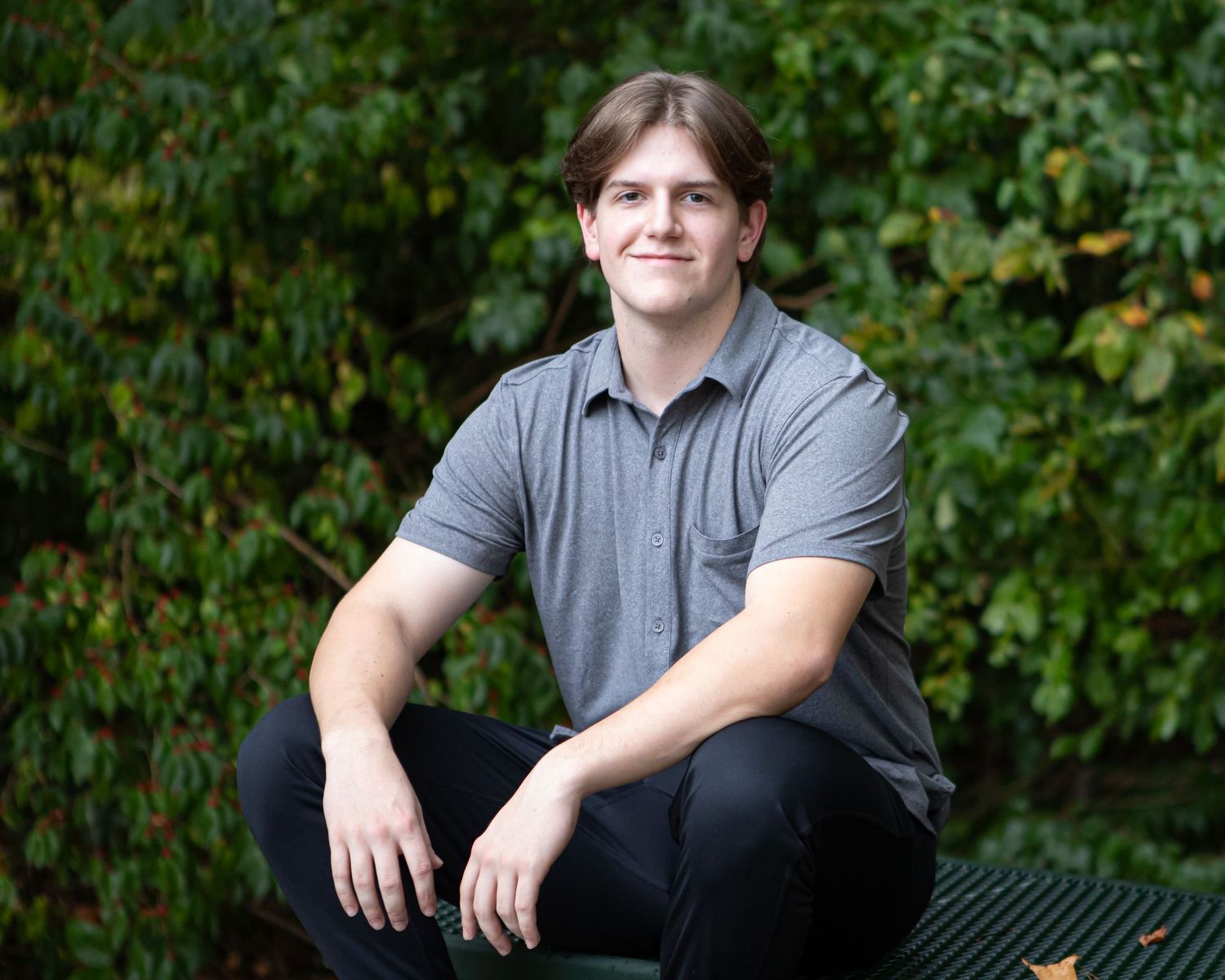 Portrait series showing someone in casual grey attire against a natural green background.
