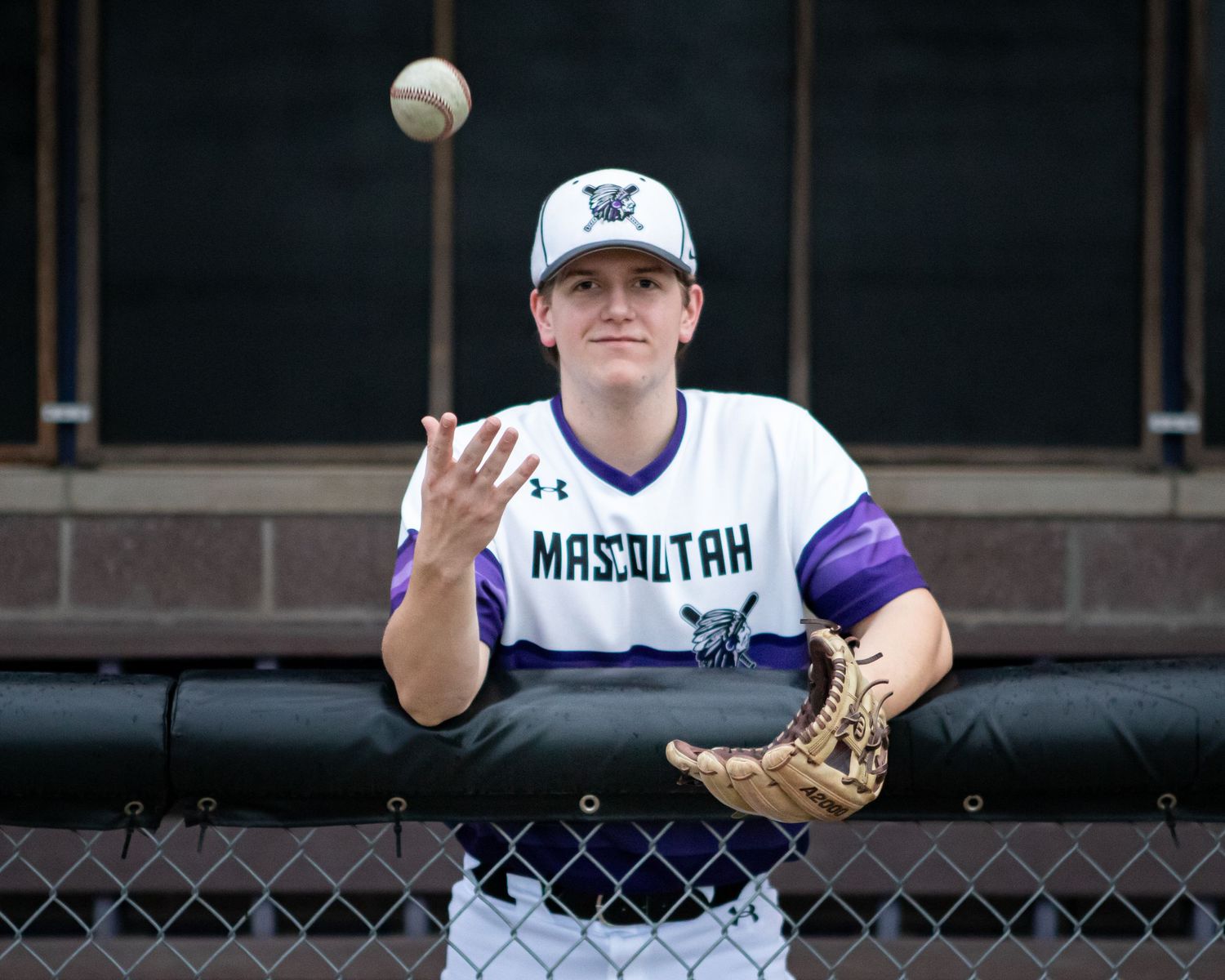 Baseball player practicing catching drills against a dark background.