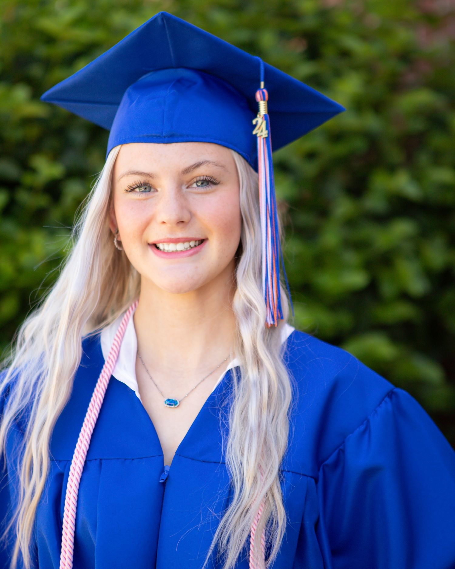 Graduation photos in bright blue cap and gown with tassel and honor cords.