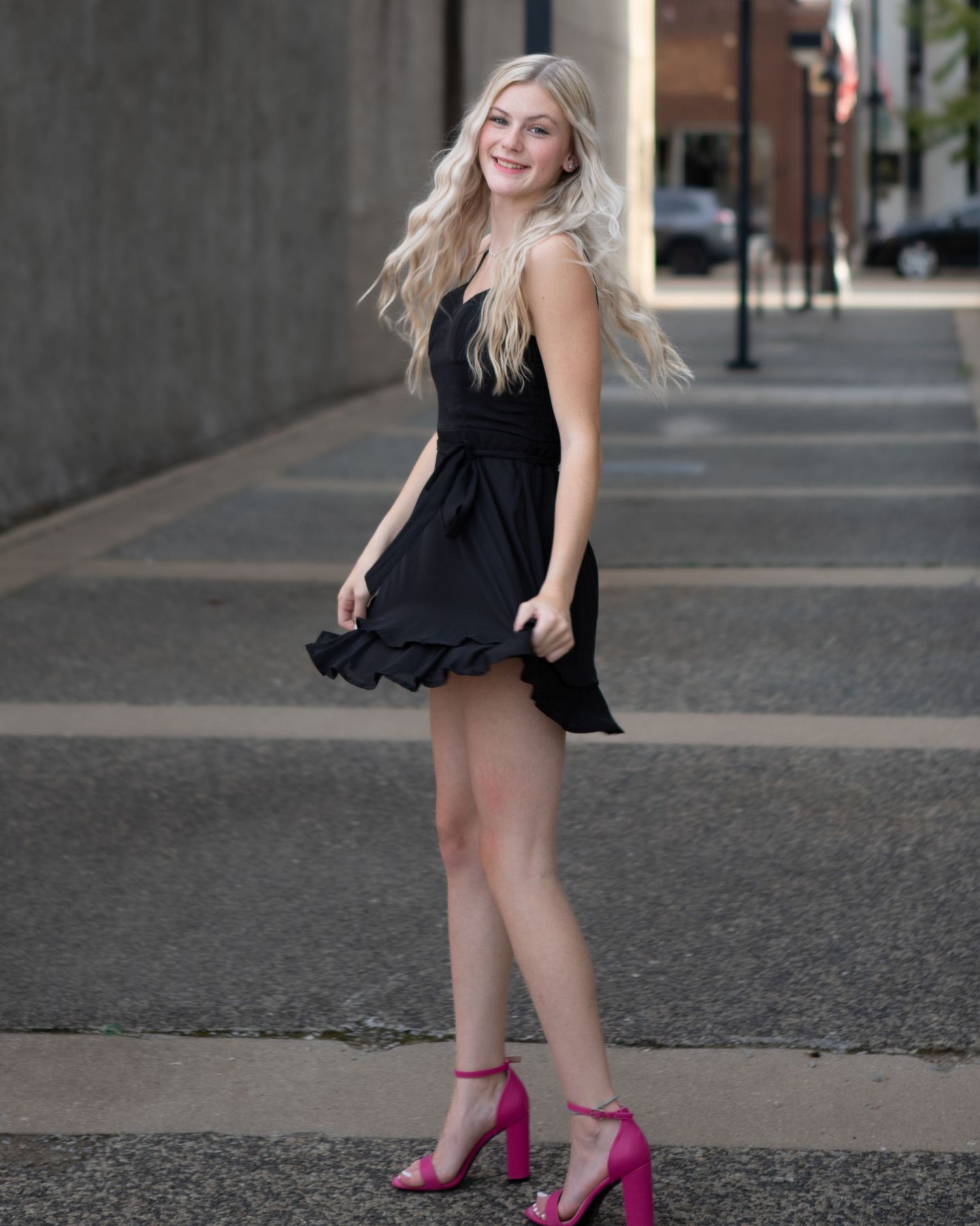 Fashion portrait with bright pink heels against urban backdrop.