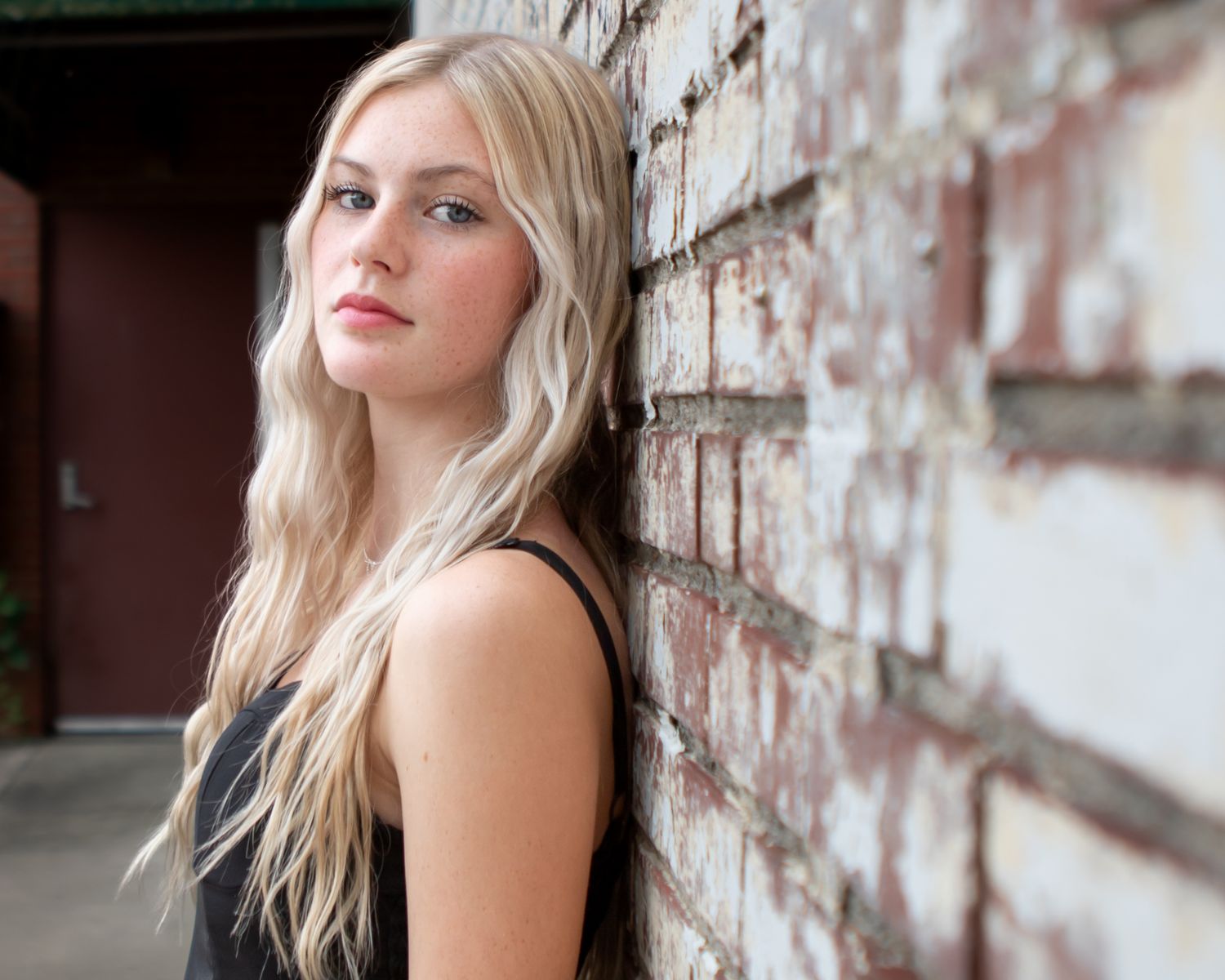 Outdoor portrait session against weathered brick wall.
