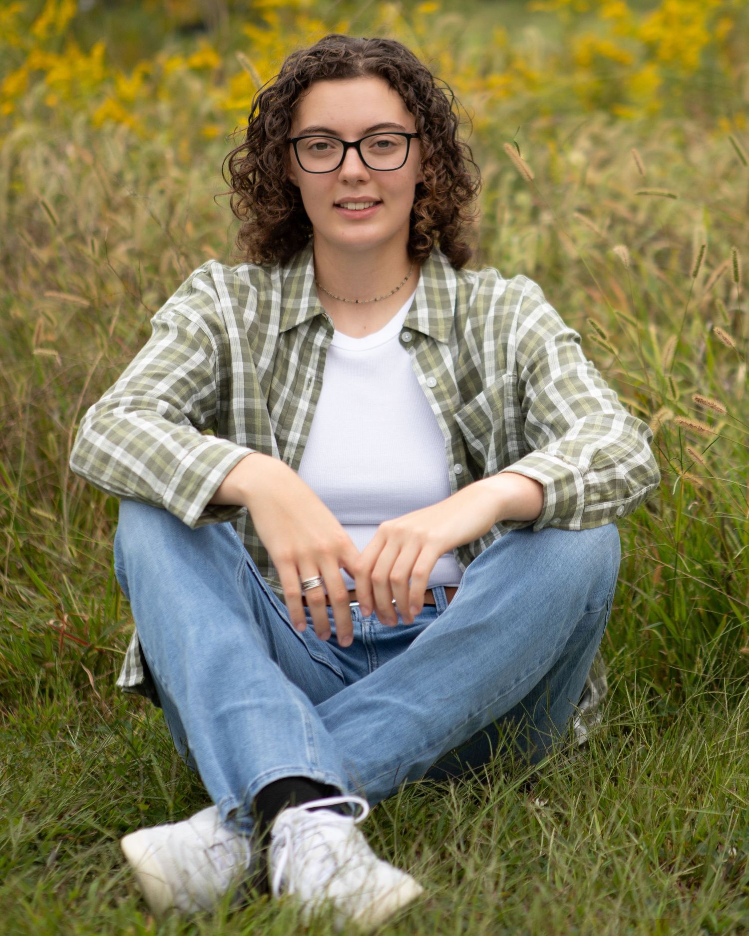 Casual outdoor portraits in plaid shirt and jeans among yellow wildflowers.