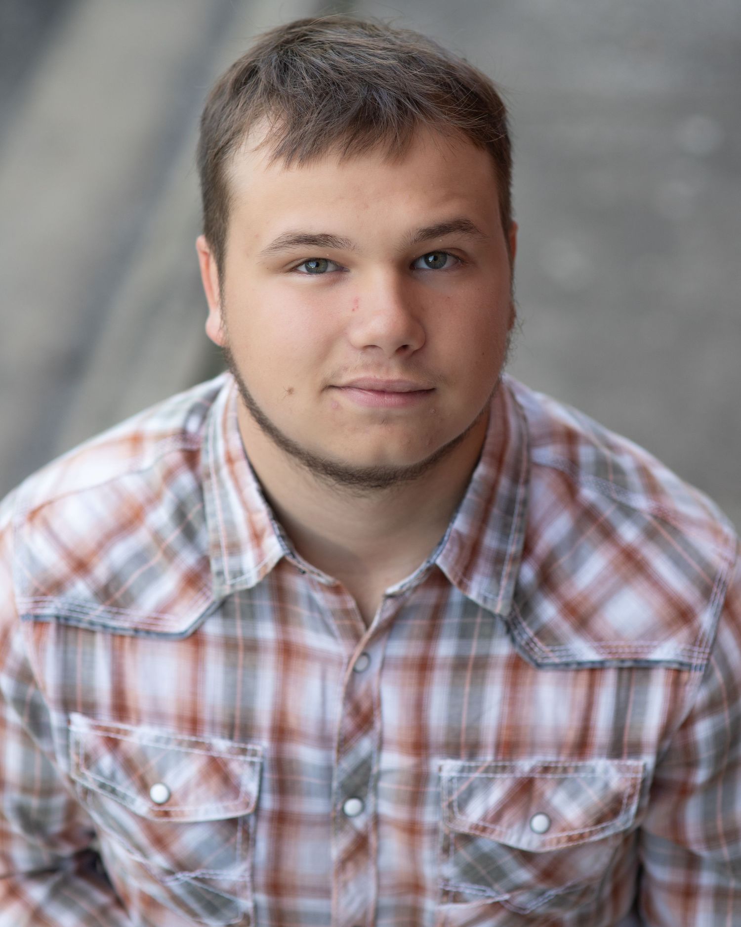 Close-up portrait series wearing plaid button-up shirt against grey background.