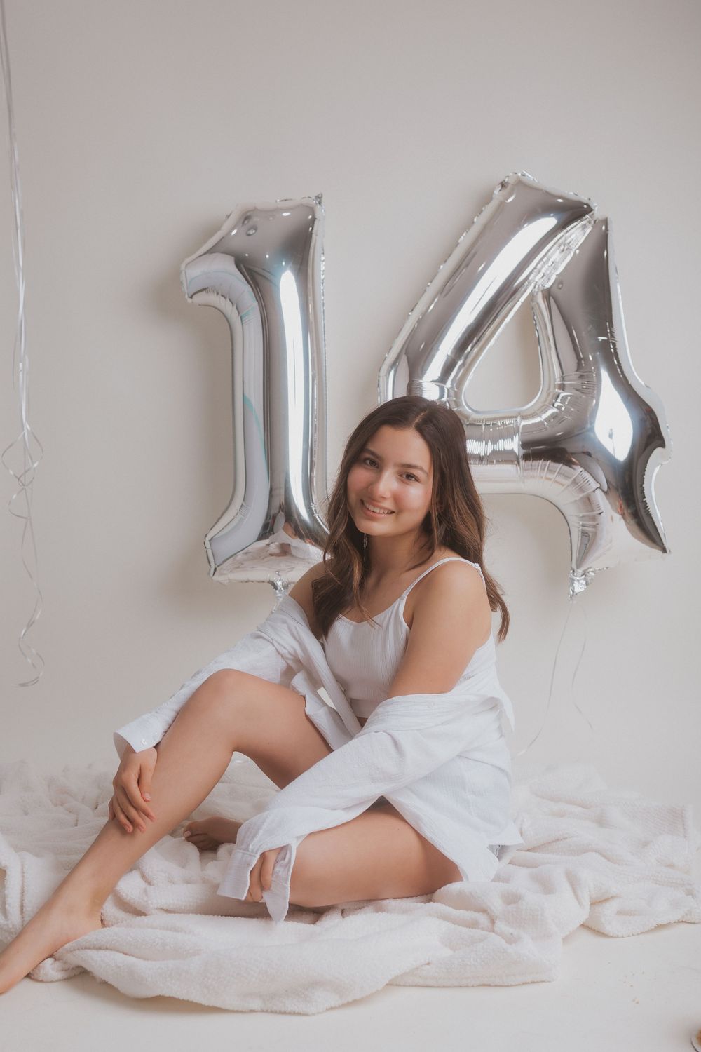 Celebratory portrait with silver number 14 balloons and white decor.
