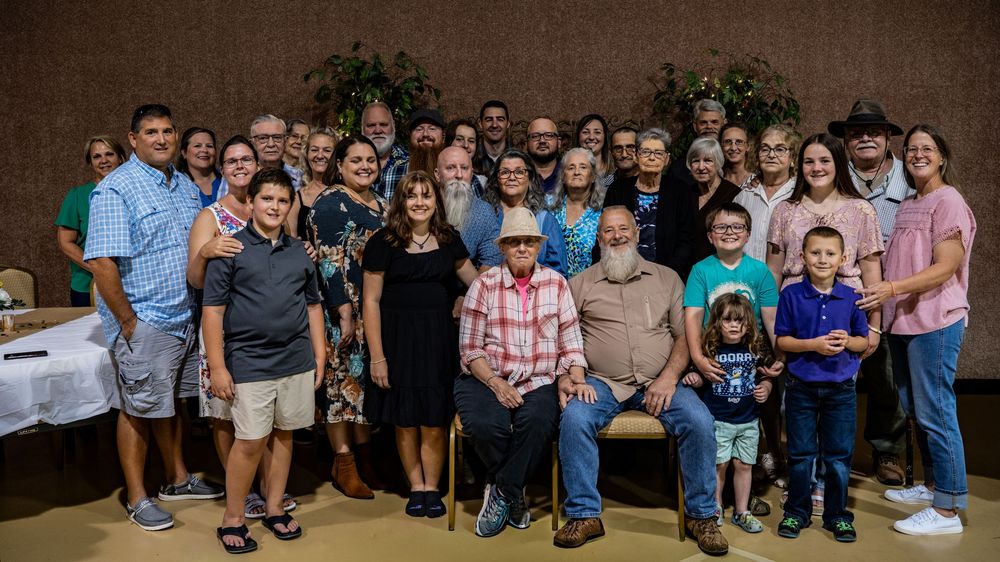 A large group gathers together for a celebratory event in a dark room.