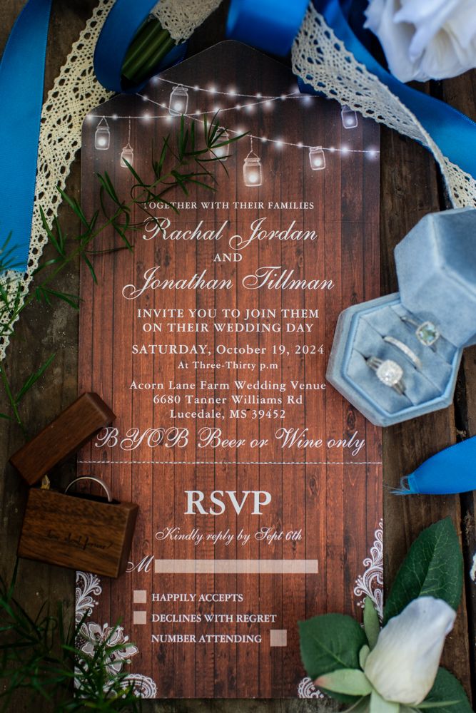 Rustic wooden wedding invitation with string lights design and lace details surrounded by floral decor and RSVP card.