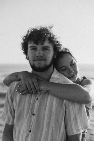 Black and white intimate portrait of couple sharing tender embrace on beach.
