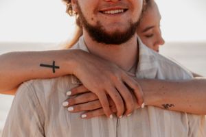 Close-up shot of hands with small tattoos showing affection and connection.