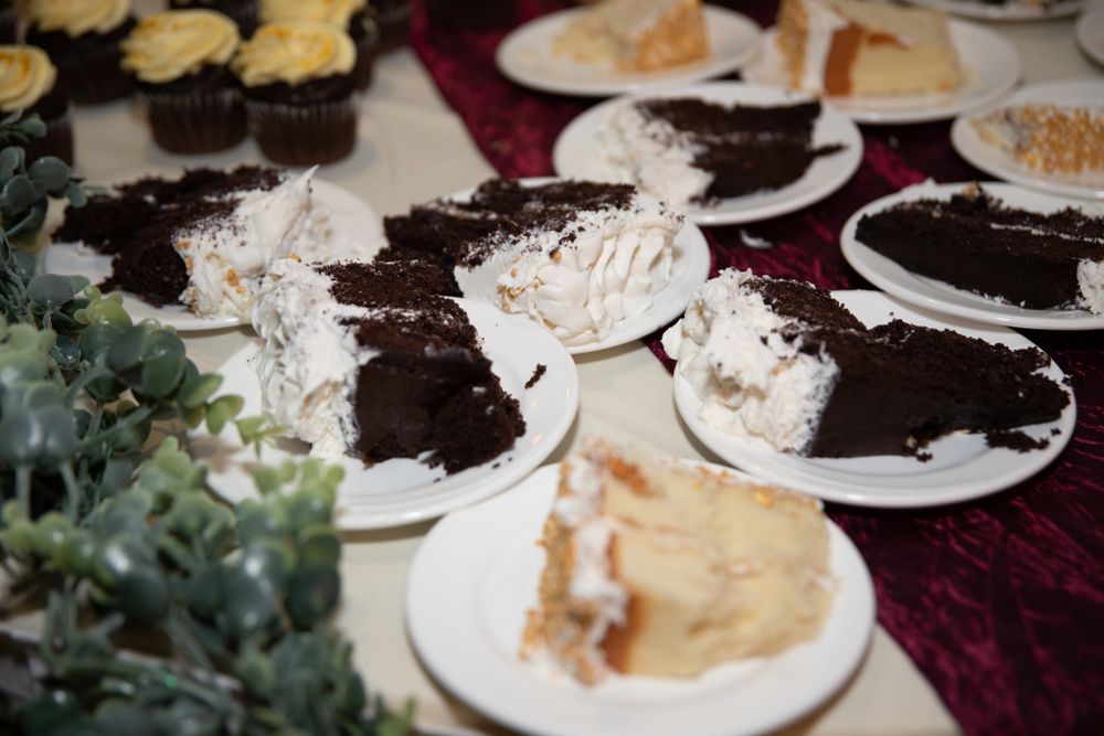 Chocolate desserts and cakes displayed on burgundy tablecloth at wedding reception.