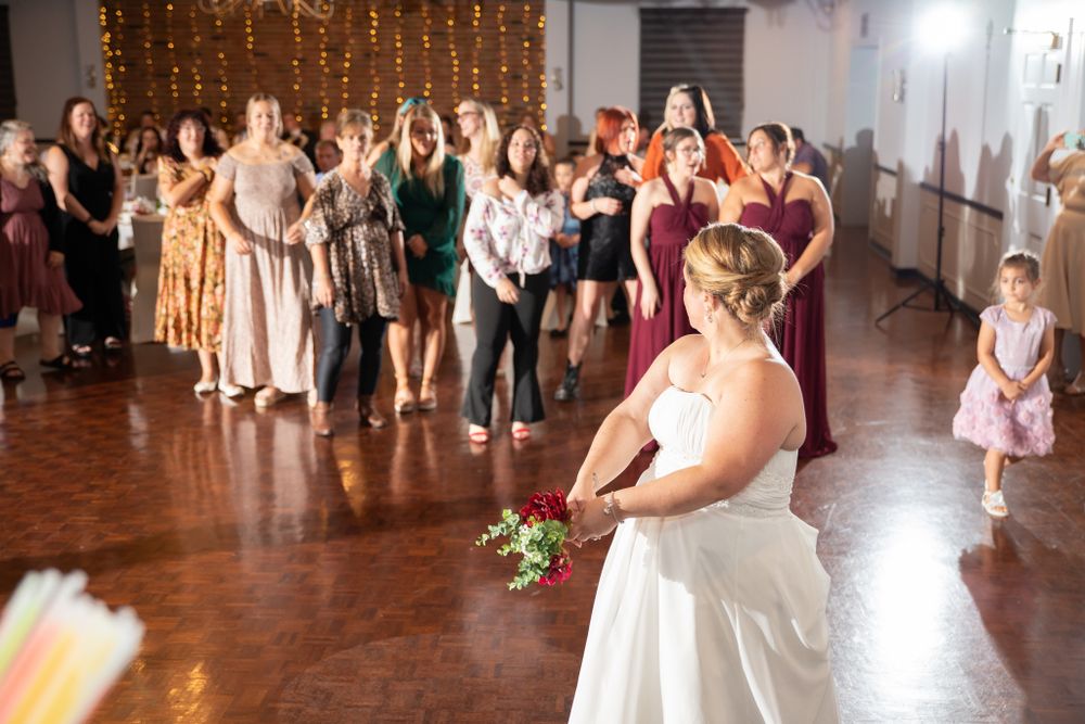 A traditional bouquet toss moment at a wedding reception with excited guests.