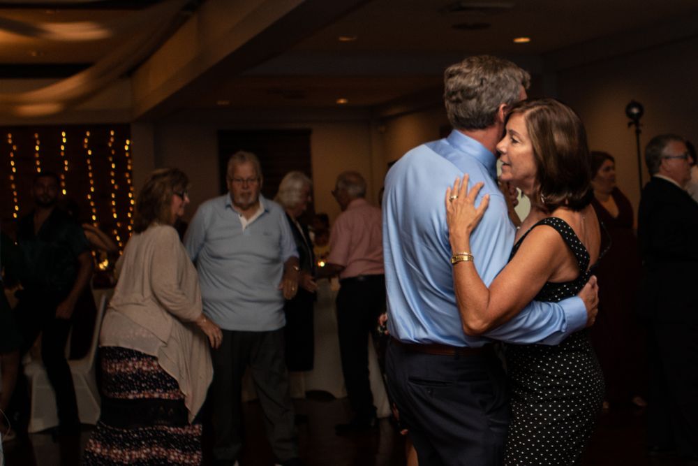 Couples slow dancing at a wedding reception with string lights in the background.