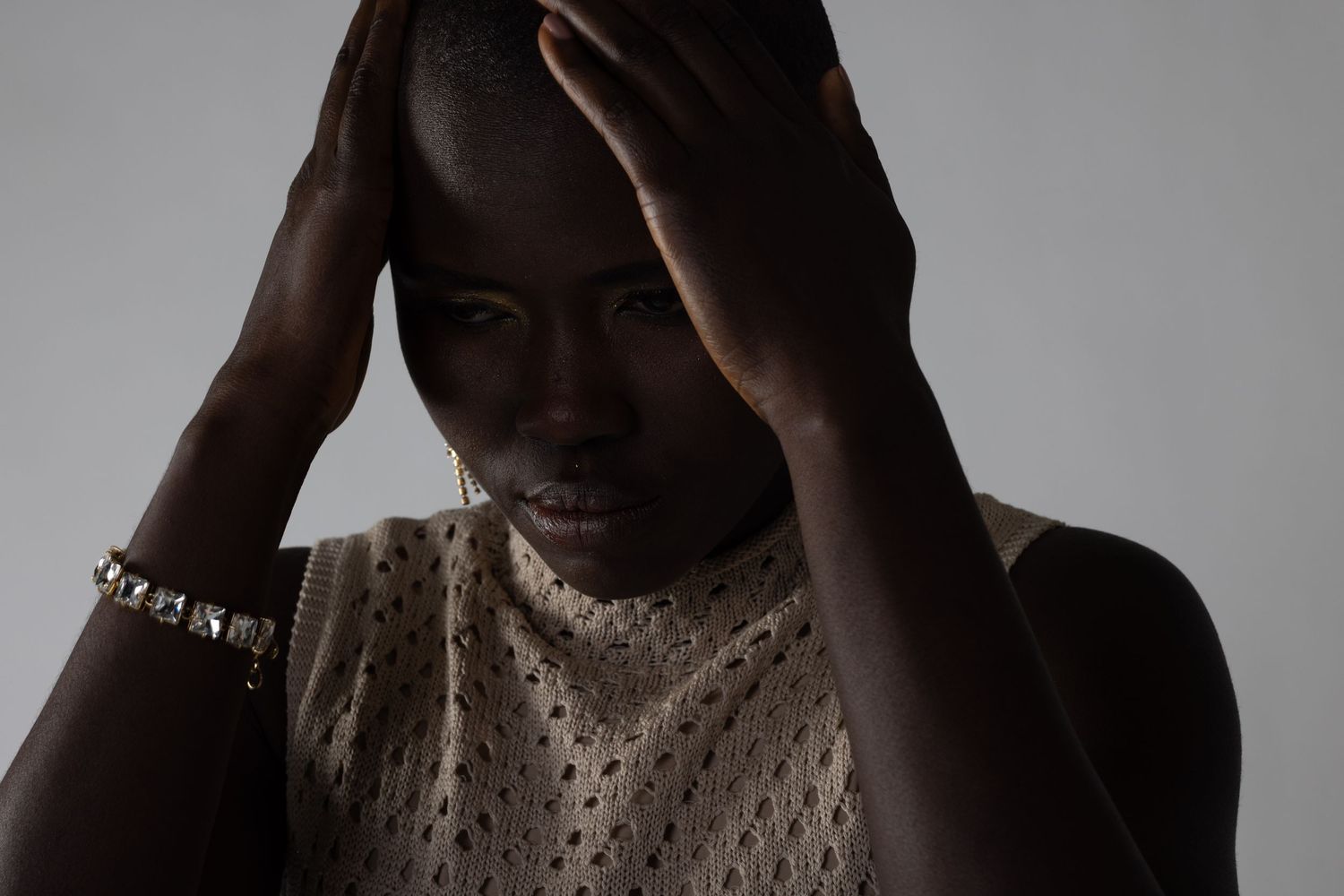 Artistic portrait with dramatic shadows showing textured top and delicate jewelry.