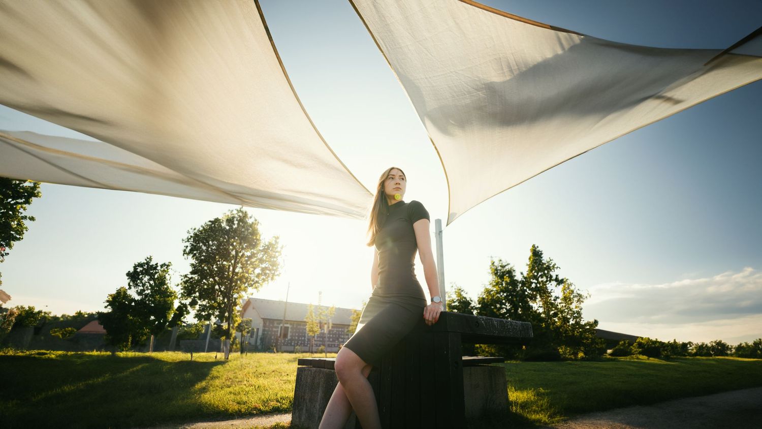 Portréfotó egy fiatal nőről szabadtéren, naplementében, fehér textil alatt pózolva.