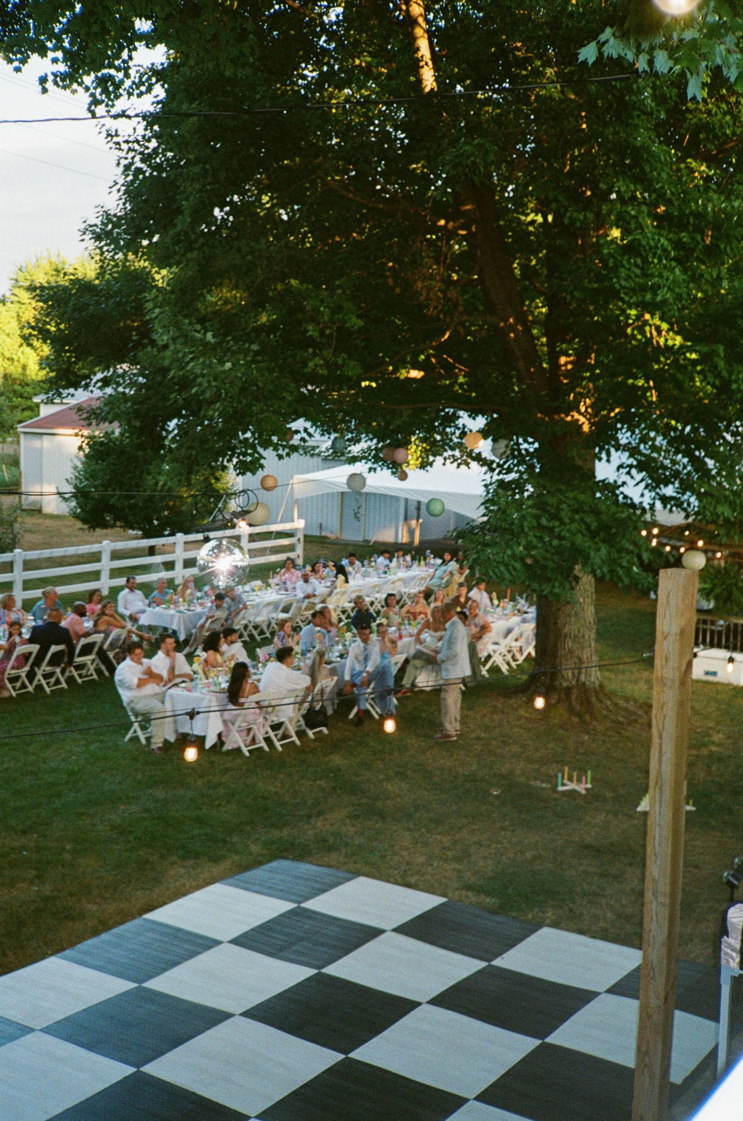 An industrial wedding reception venue with string lights and gold chairs at round tables.