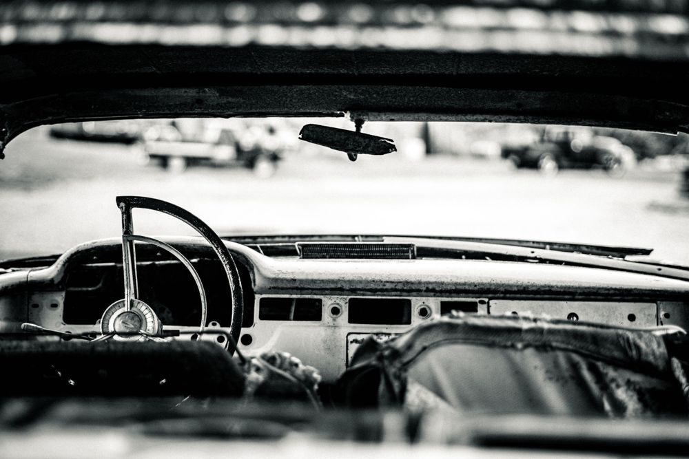 Interior dashboard view of a classic car shot in black and white.