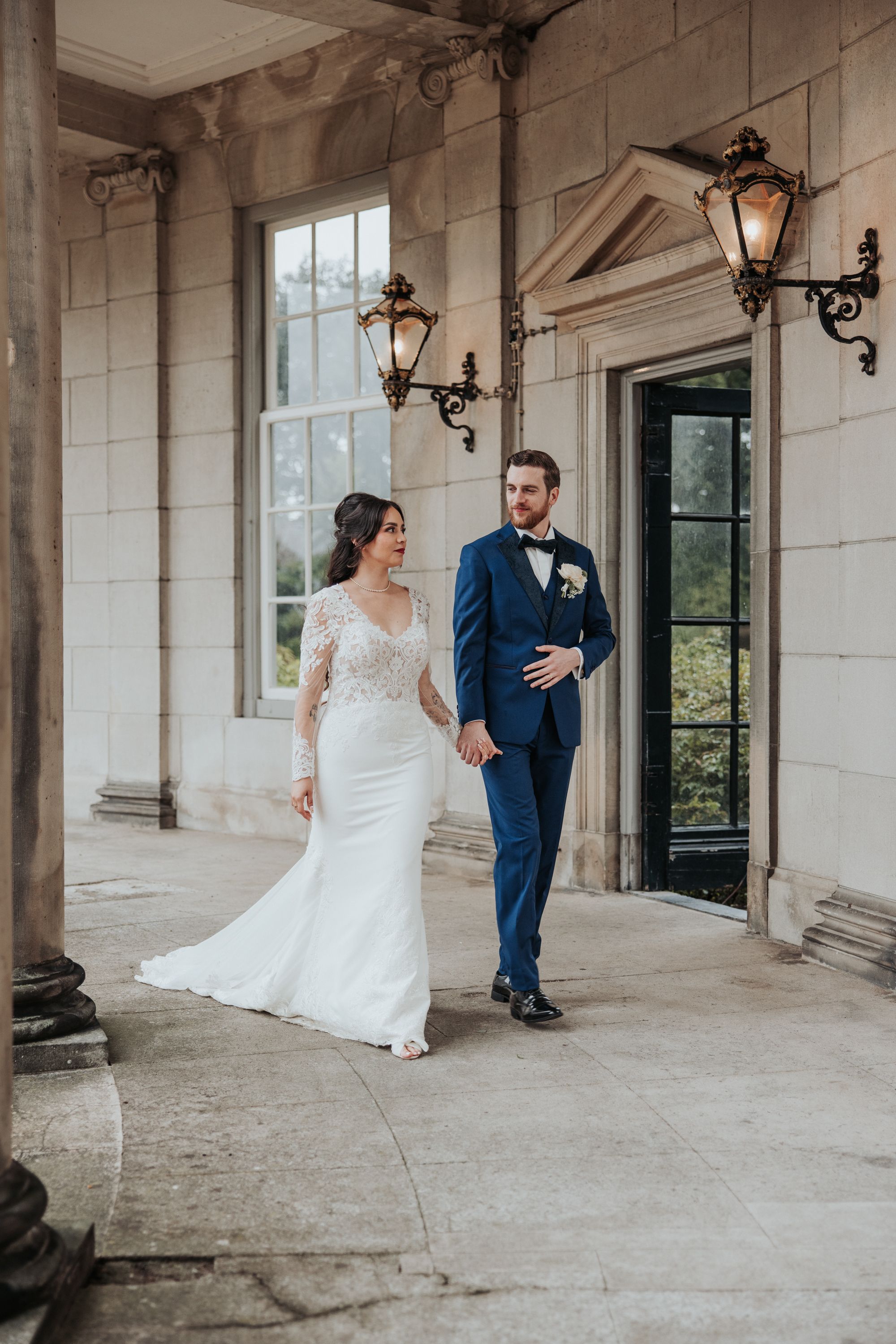Elegant wedding couple holding hands and posing naturally walking at the entrance of Landgoed De Voorst during couple portraits