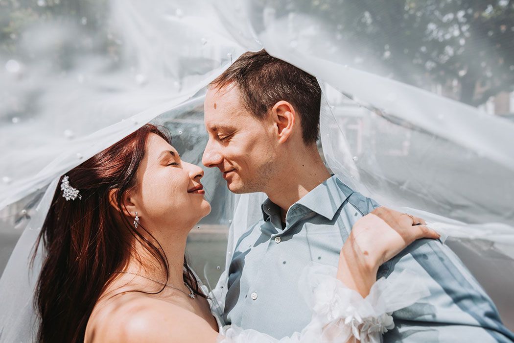 Wedding couple sharing intimate moment under veil.