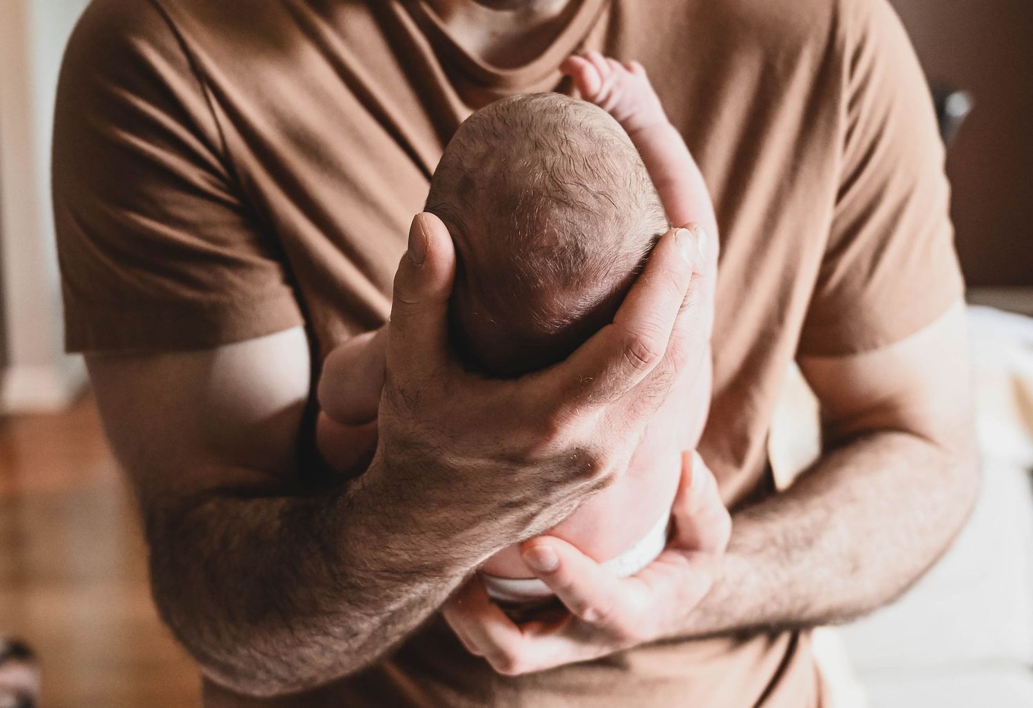 Dad's hands holding baby in Lifestyle newborn photo shoot in Albany, NY with K. Manchuck Photography