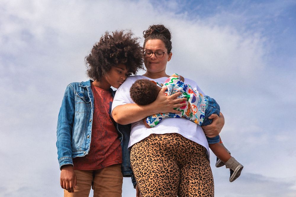 Family shares an intimate moment against a bright blue sky background.