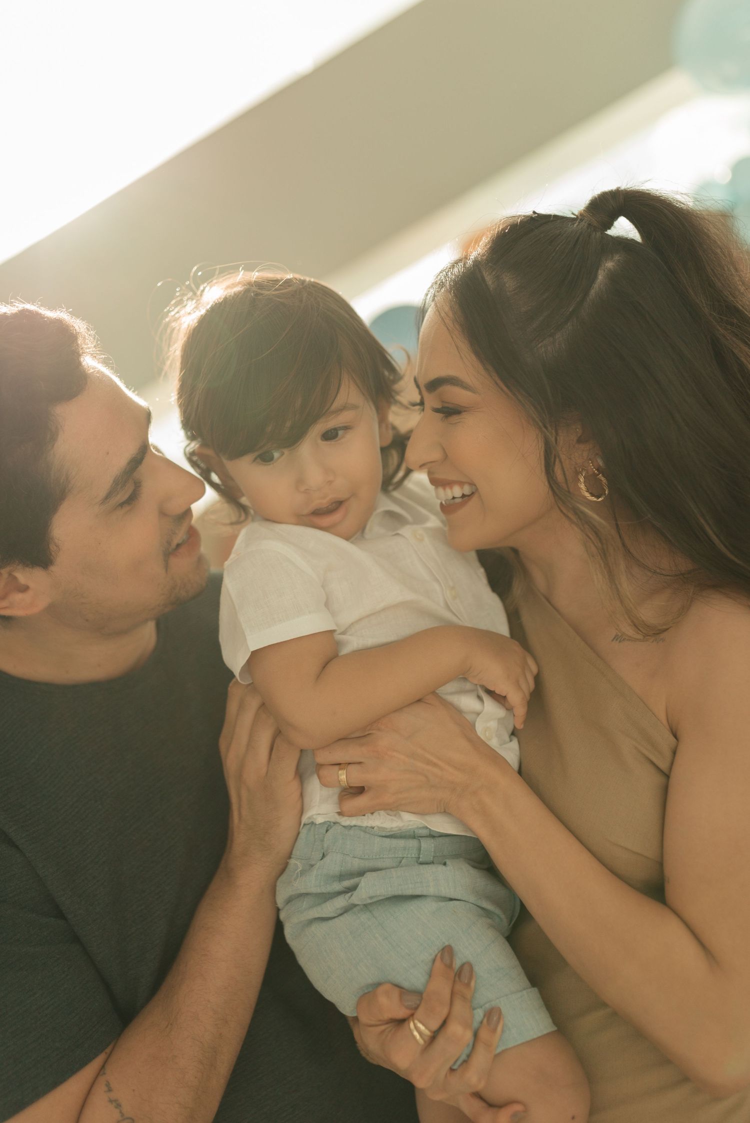 Intimate family portrait with parents sharing a tender moment with their young child.