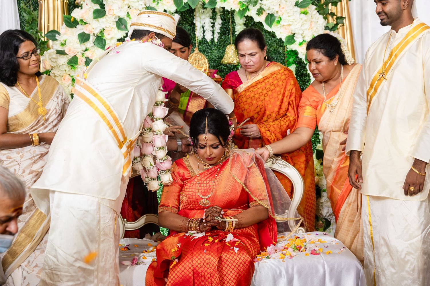 Traditional South Asian wedding ceremony with guests in traditional attire performing rituals.