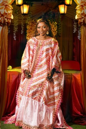 Glamorous pink and white patterned kaftan dress photographed in luxurious setting with golden throne.
