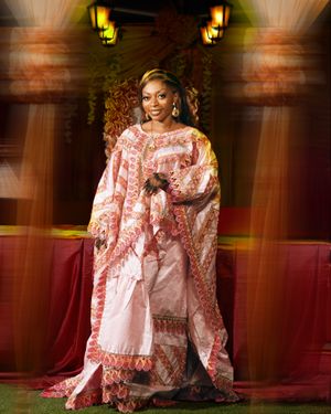 Elegant formal portrait featuring pink and white patterned kaftan in dramatic lighting.