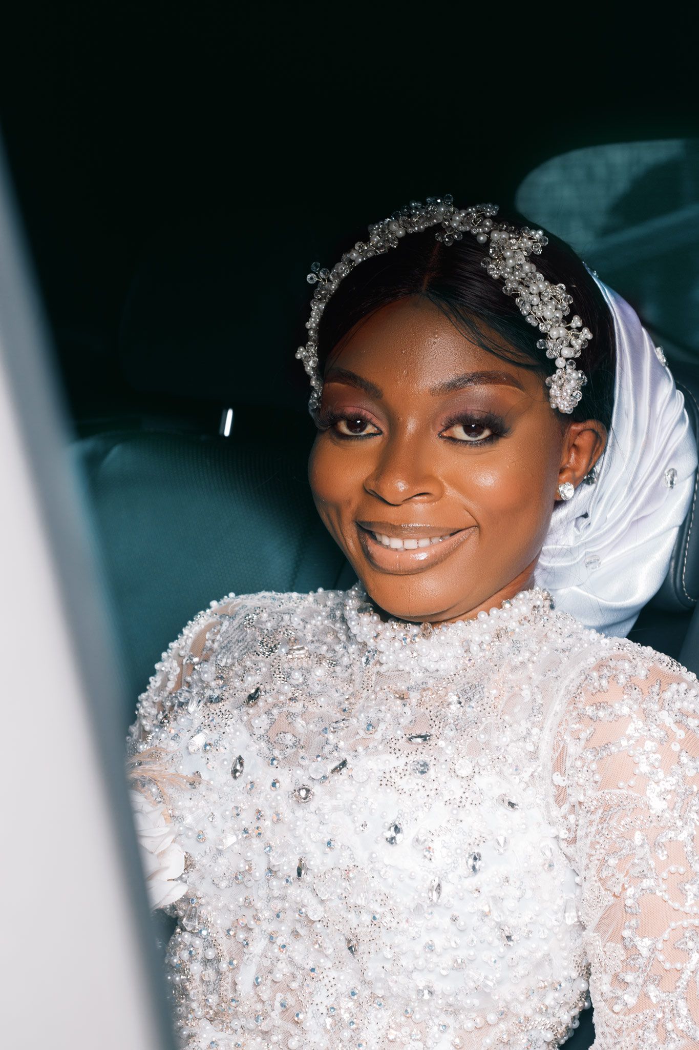 Bride wearing crystal headpiece and high-neck lace gown with delicate beading details.