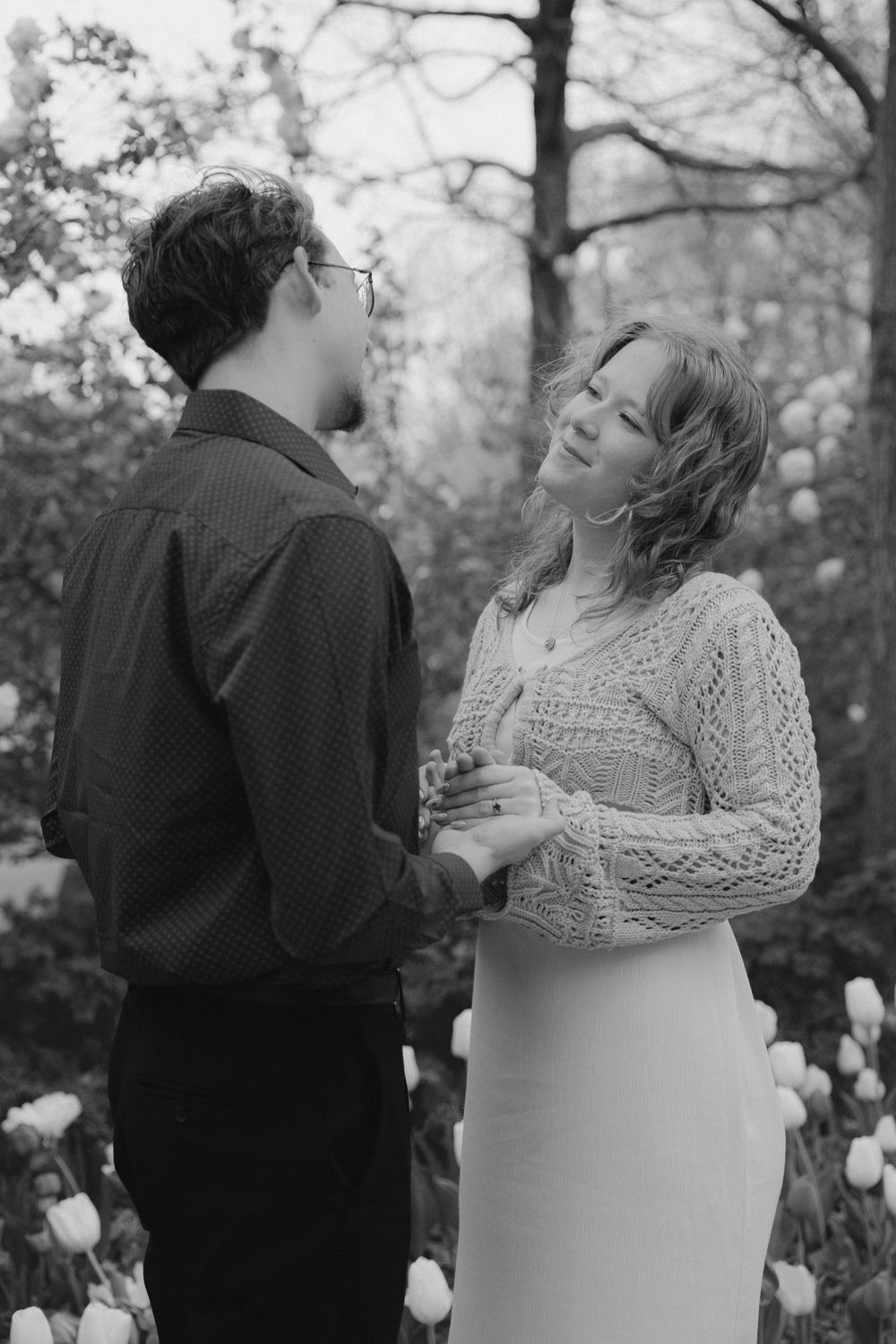 Black and white portrait of couple sharing romantic moment among spring tulips.