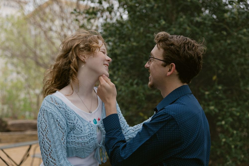 An intimate moment captured between two people in a garden setting.