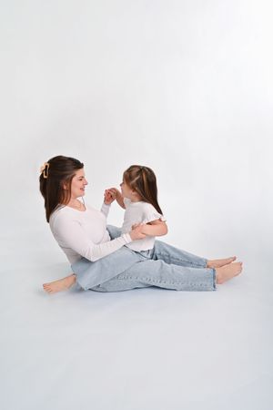 Two people lying on their stomachs reading books together against a white background.