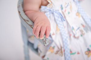 Close-up detail of fabric pattern with delicate floral and bird motifs in soft blue tones.