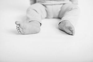 Black and white image of tiny baby feet against white backdrop.