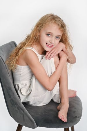 Person in white top relaxing on grey chair with casual pose.