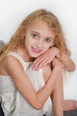 Person in white sleeveless top posing casually on grey furniture.