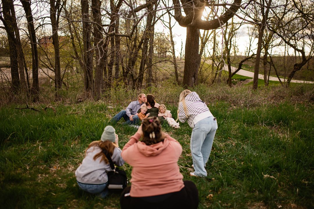 Family gathering outdoors in a wooded area during golden hour for a candid photo session.