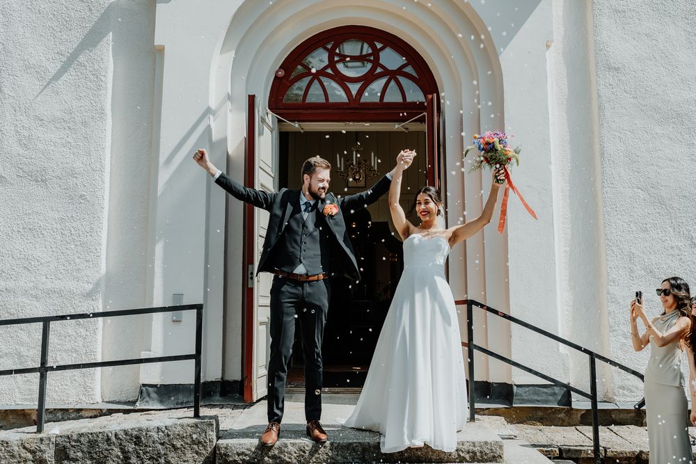 Brudpar gratuleras på trappan till Järstorps kyrka, under ett bröllop i Jönköping. Fotograf Veronica Eng var bröllopsfotograf.
