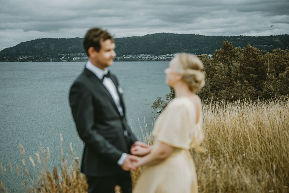Brudpar står vid Rosenlunds bankar i Jönköping och man ser Vättern och Huskvarna i bakgrunden.