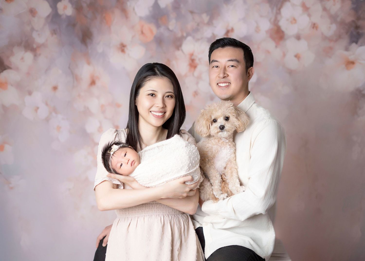 Newborn family photography Covina CA parents holding baby with dog in studio floral backdrop