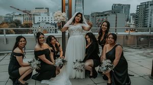 Wedding party gathered on an urban rooftop with city buildings visible in the background.