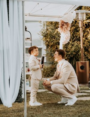 A sequence of candid moments between two people in white outfits sitting on grass near flowing white curtains.