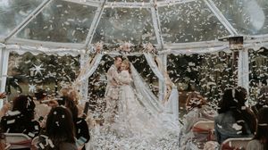 Wedding celebration scene with guests throwing confetti in the air during an outdoor reception.