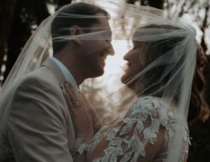Romantic black and white wedding portrait series showing tender moments between bride and groom through a delicate veil.