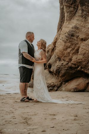 Wedding photos captured on a moody beach with towering cliffs and overcast skies.