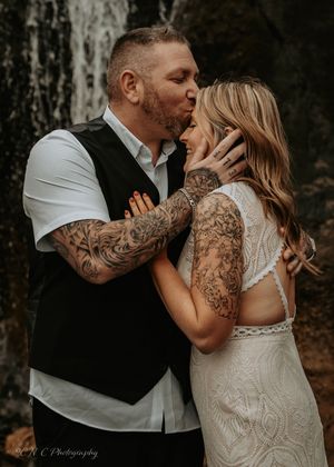 Romantic couple embracing in a dark wooded setting wearing formal attire.