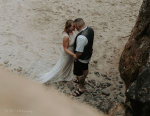 Romantic beach photoshoot with dramatic coastal cliffs and overcast lighting.