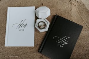 Wedding stationery and invitation suite featuring black and white cards with elegant calligraphy laid out on a textured surface.