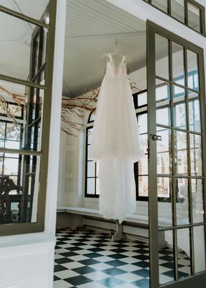 Interior view of a modern venue space with black and white checkered floor and floor-to-ceiling windows displaying hanging dresses.
