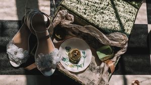 Overhead view of coffee and pastry on rustic table with cozy blanket and boots in dark moody lighting.